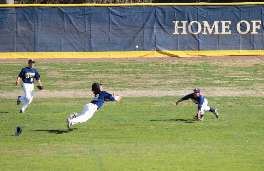 Vela (center) dives for a ball in center field. Photo by John Lee.