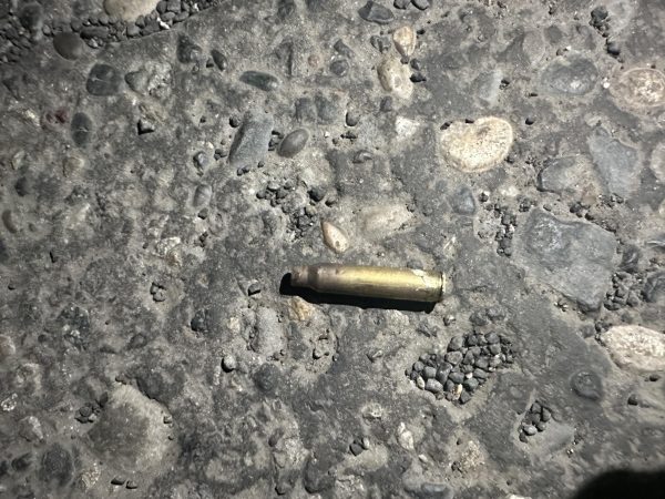 A bullet casing from what may have been an anonymous style weapon lies on the rocky sidewalk near the frats.